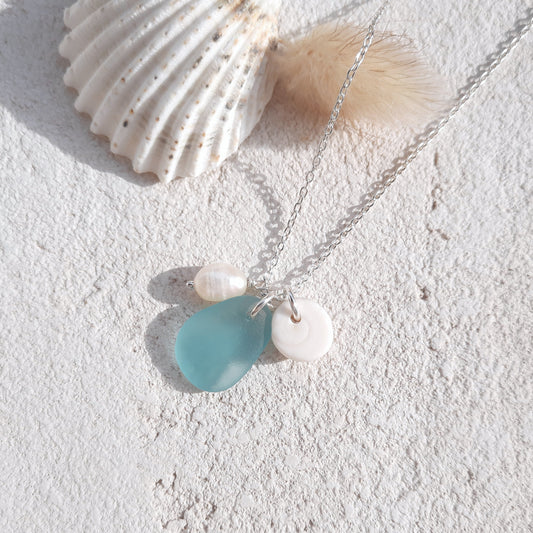 Silver chain necklace with a aquamarine sea glass pendant and shiva eye shell and pearl charms 