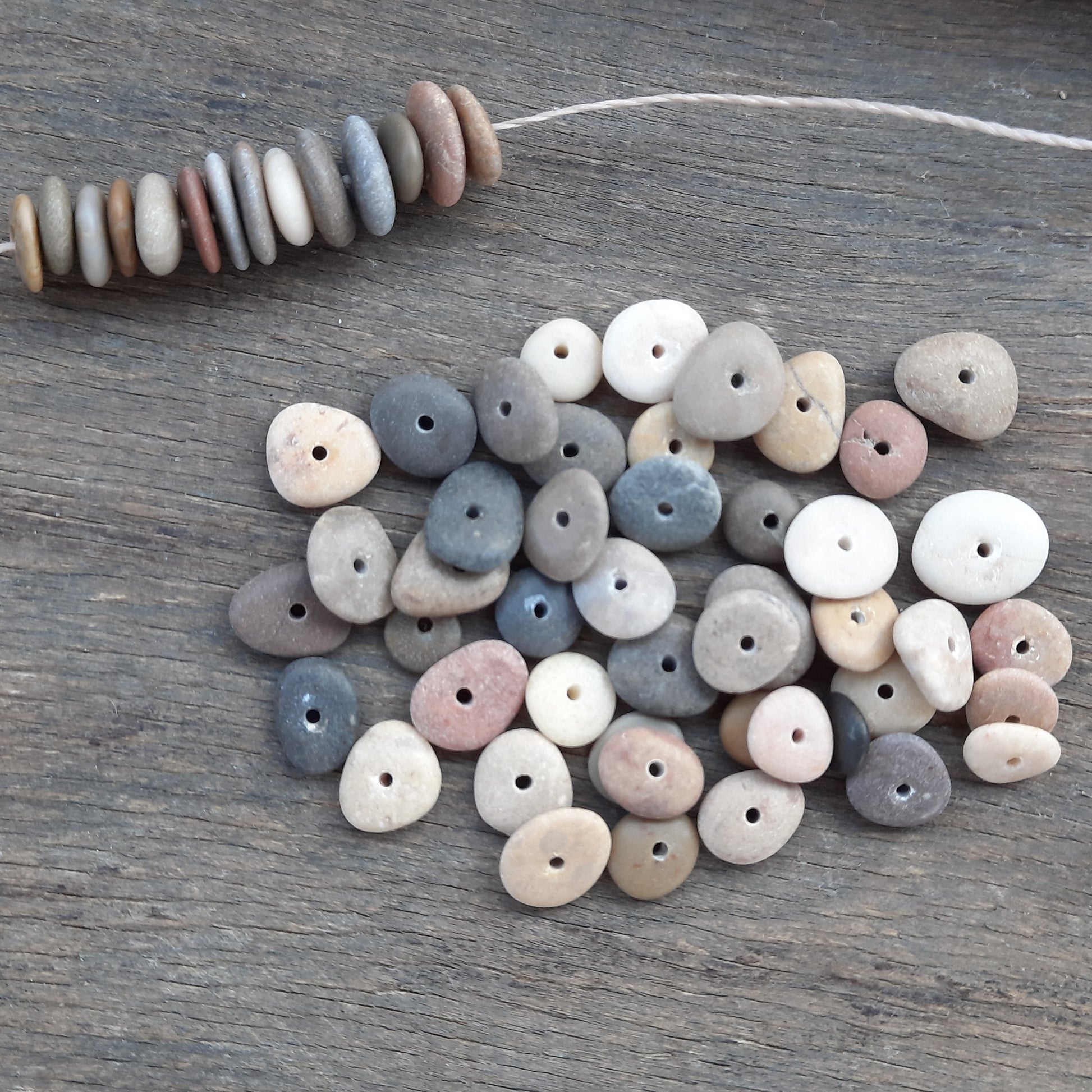 Collection of multicolored asorted natural stone beads on a wooden surface