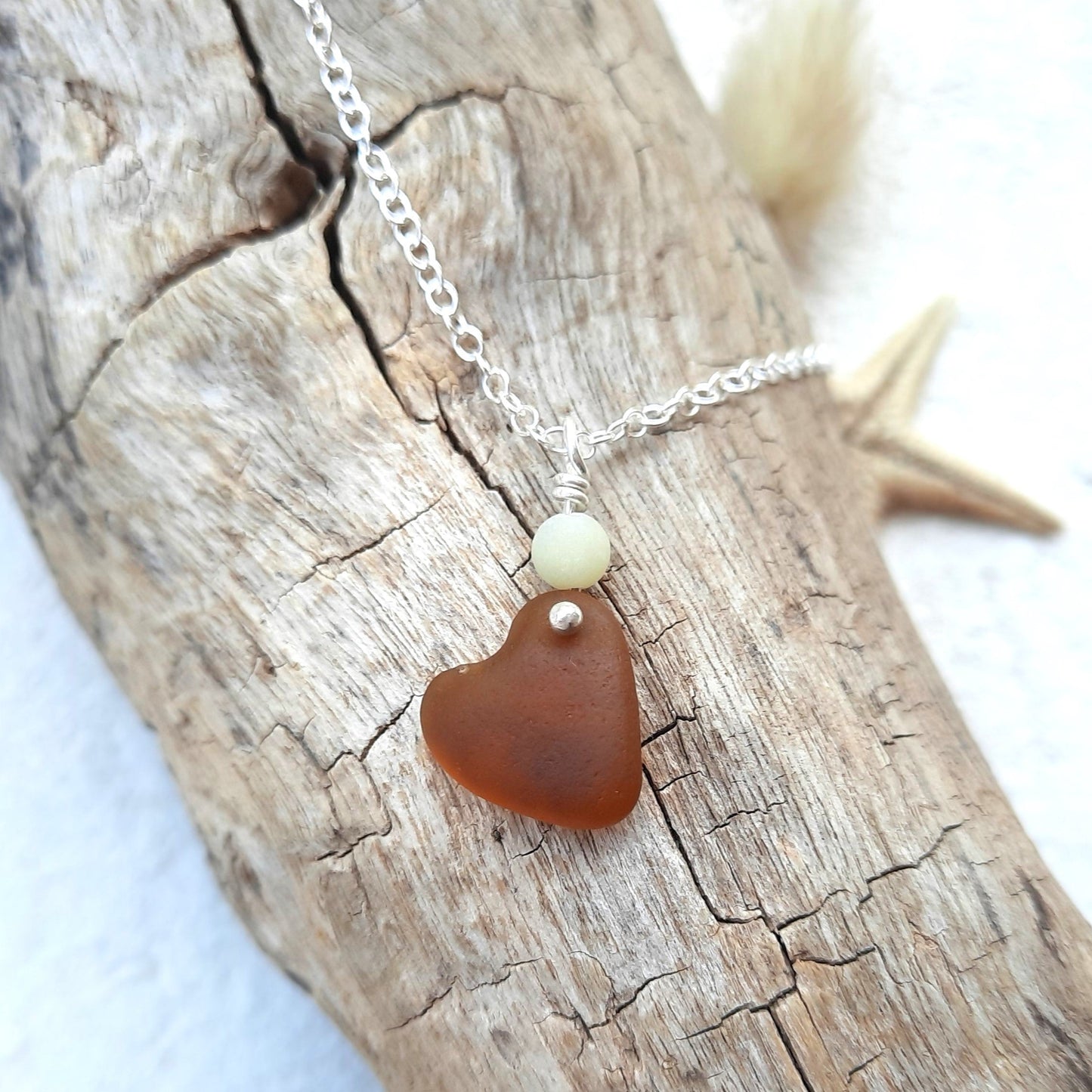 Necklace with a heart-shaped brown genuine sea glass pendant on a piece of driftwood