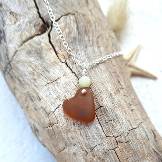 Necklace with a heart-shaped brown genuine sea glass pendant on a piece of driftwood