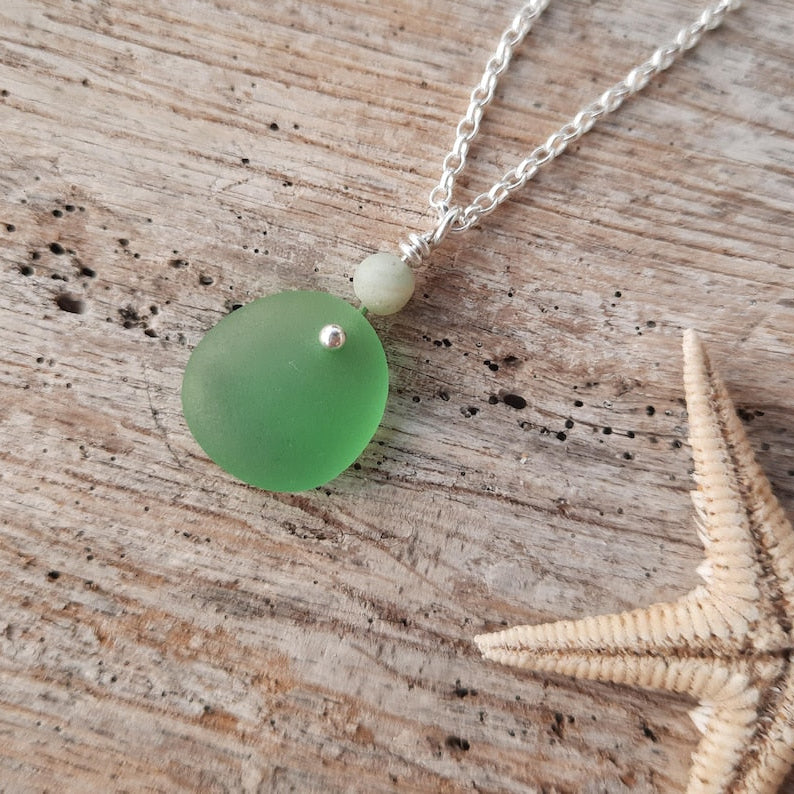 Necklace with a green genuine sea glass pendant on a wooden surface